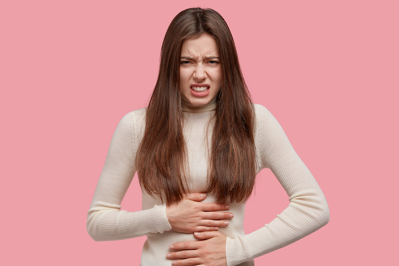 Unhappy woman holding her stomach because she might possibly have a bowel obstruction.