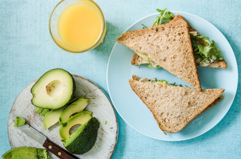 A plate of avocado with a sandwich and some orange juice. Avocado is great to eat after you break your fast.