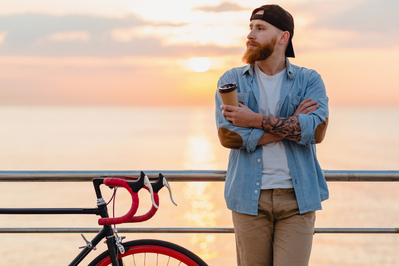 A young man takes a coffee break after his cycling exercise.