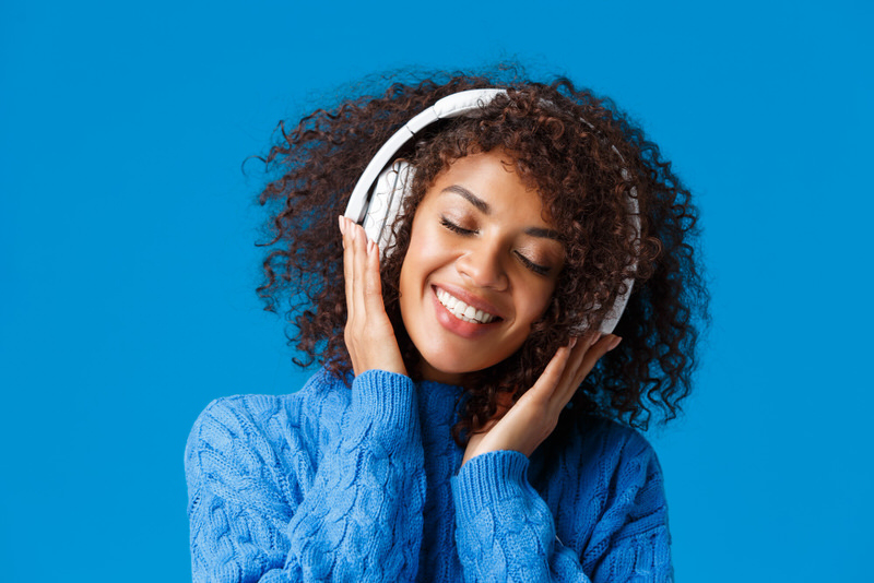 A young female is listening to wellness music on her wireless headphones