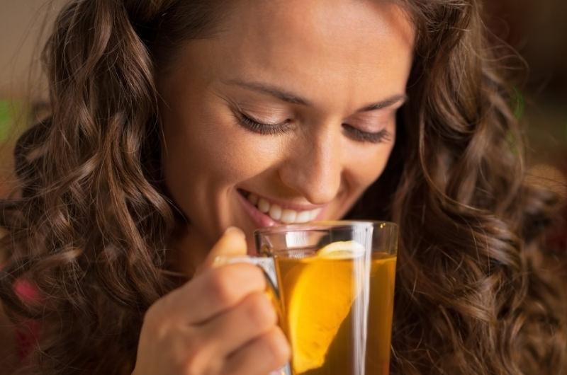 A young woman is drinking chamomile tea as an alternative to coffee, to reduce her nausea.
