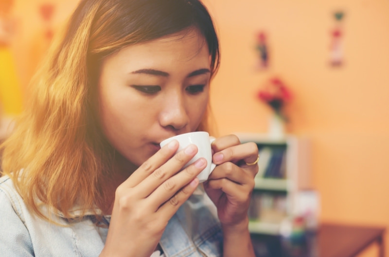 A young woman is drinking green tea to help reduce her night sweats.