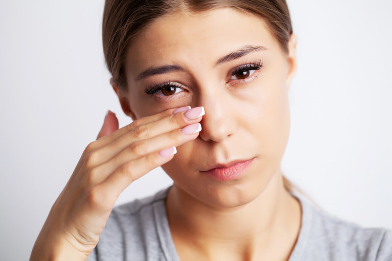 A young woman is having pain from severe eye twitching.