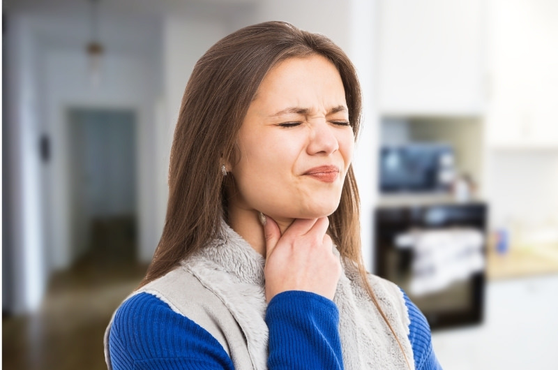 A young woman is having a weird feeling in her throat, a possible sign of the globus sensation.