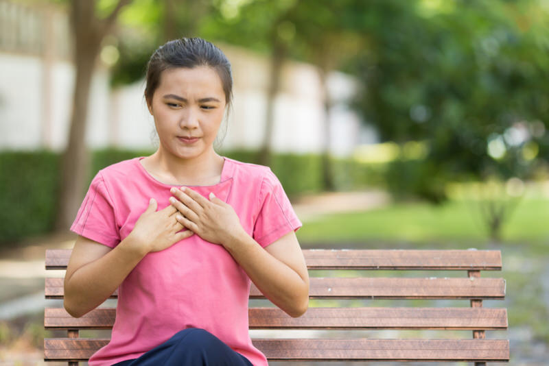A young woman sat down on a bench at the park after feeling acid reflux like symptoms.