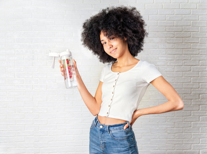 A young girl is drinking fruit-infused water to help ease her nausea everything she drinks water.