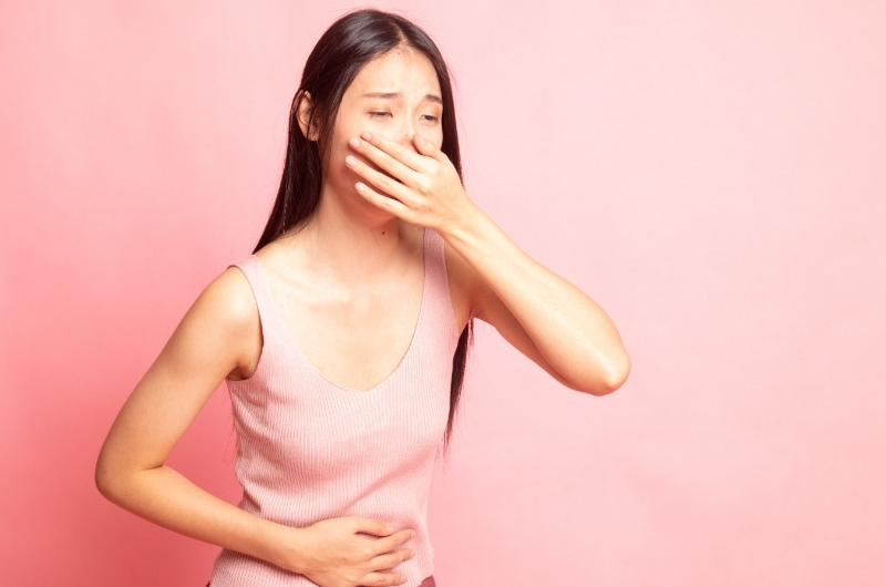 A young woman is feeling nauseous after having frequent vomiting occurrences, making her ribs ache.