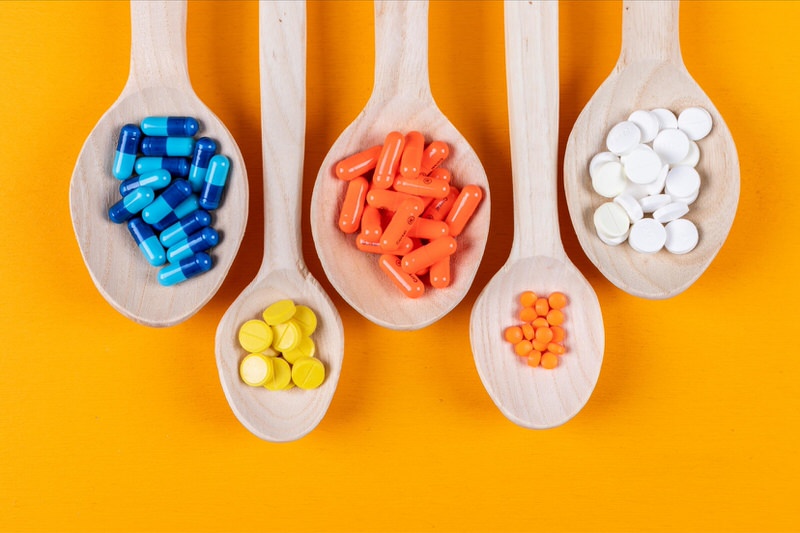 A variety of different types of pills are laid out on different wooden spoons to show their differences .