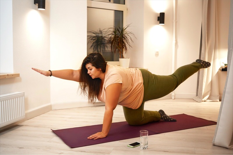 A young woman is doing yoga to start her journey towards weight loss.