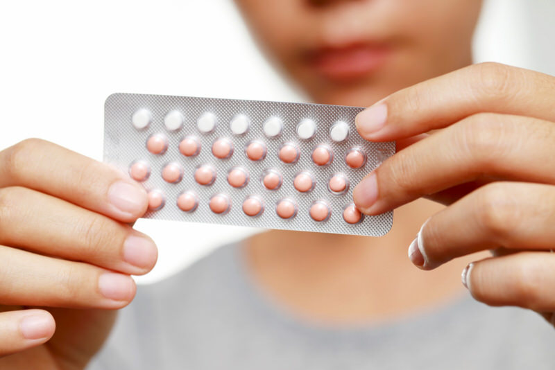 A young woman is about to take one of her birth control pills.