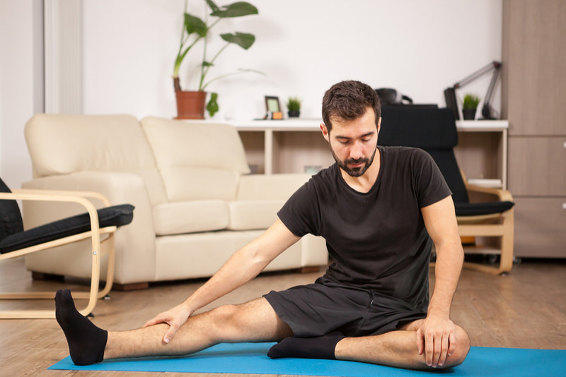 A man is on a yoga mat stretching his toes.