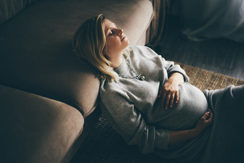 A pregnant woman is resting after using clary sage essential oil to help with her anxiety and pregnancy pain