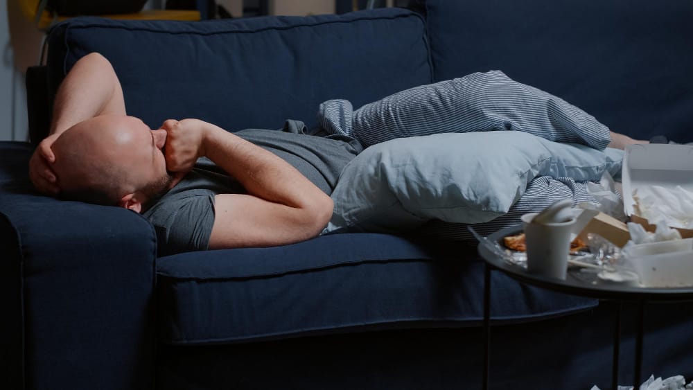 A man who is feeling high anxiety is lying on the sofa doing nothing