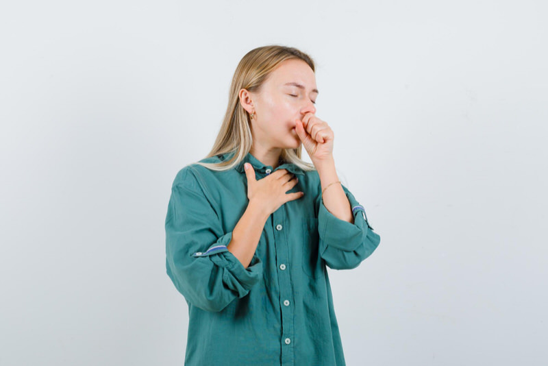 A young woman with a dry throat is coughing