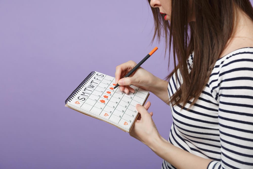 A woman is using a paper calendar to help track her fertility window