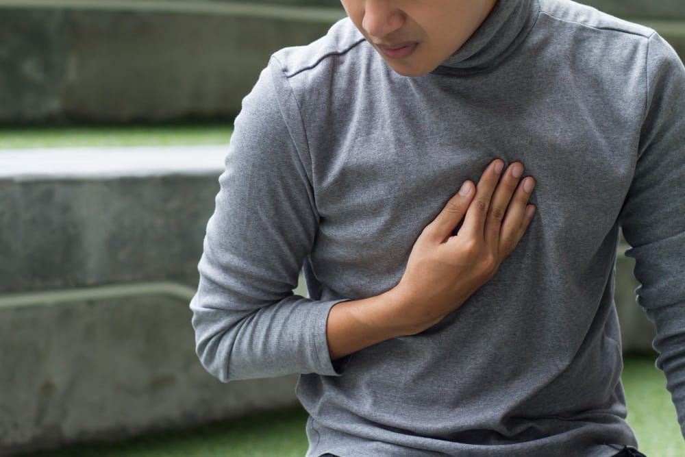 A man is holding his chest from pain due to heartburn from his acid reflux