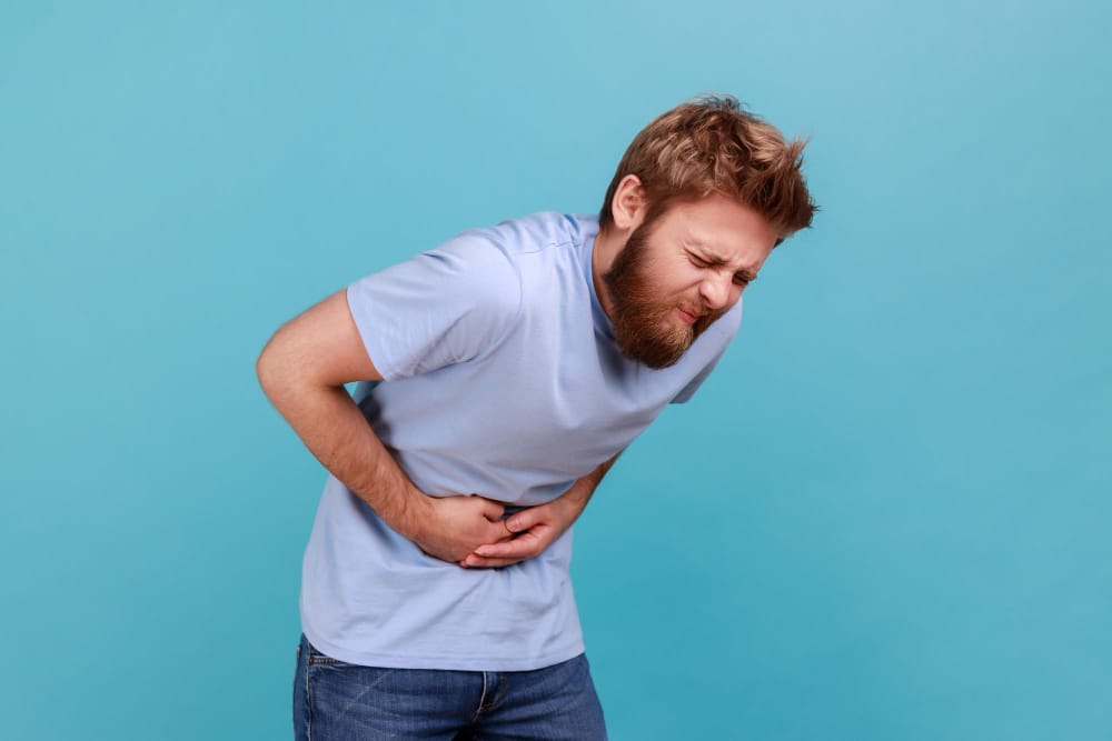 A man is bending over in pain because he's suffering from pancreatitis
