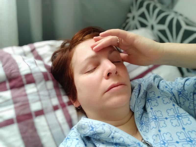 A woman is laying down with her eyes closed after feeling her blood pressure go down, a side effect of her beta blockers medicine