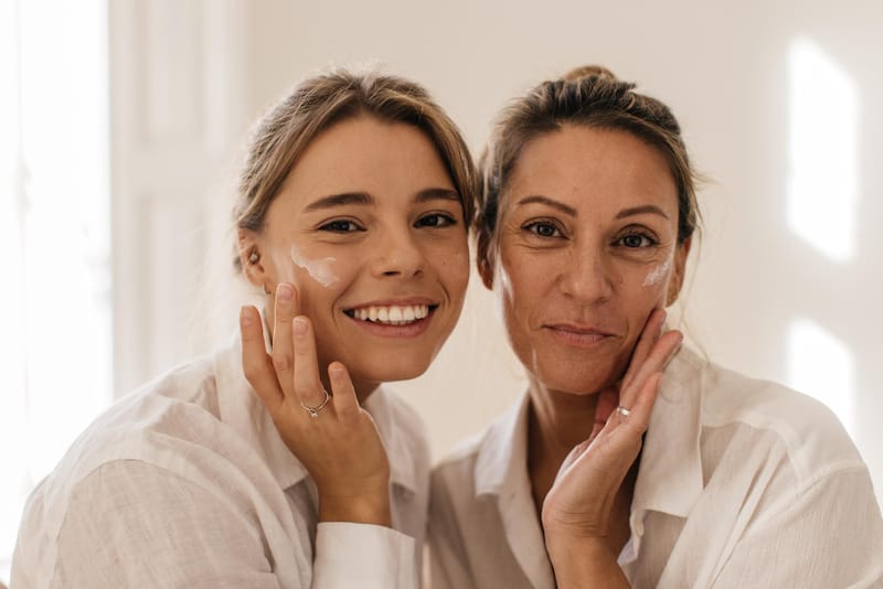 A mom and her daughter are shown applying their nighttime face cream to their face as a part of their night skin care routine