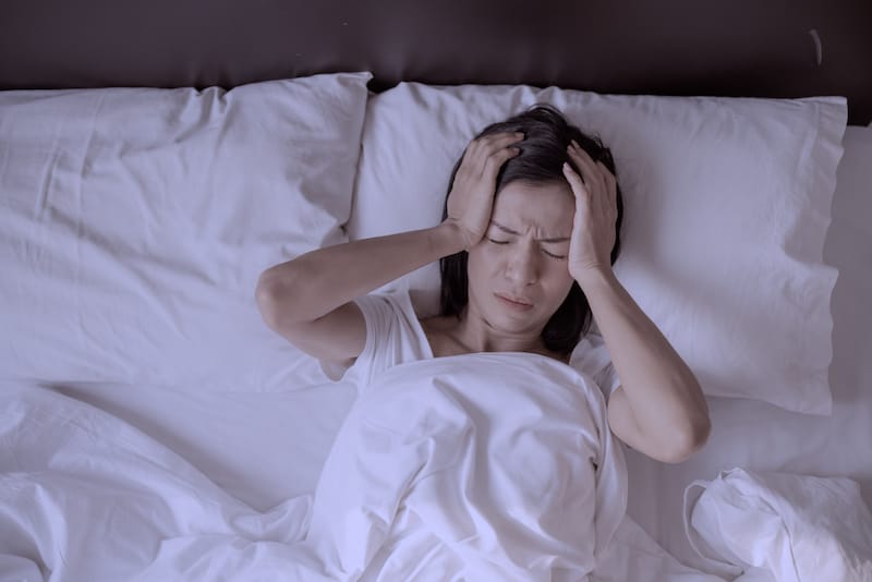 A woman is trying to sleep but is feeling insomnia symptoms due to menopause.