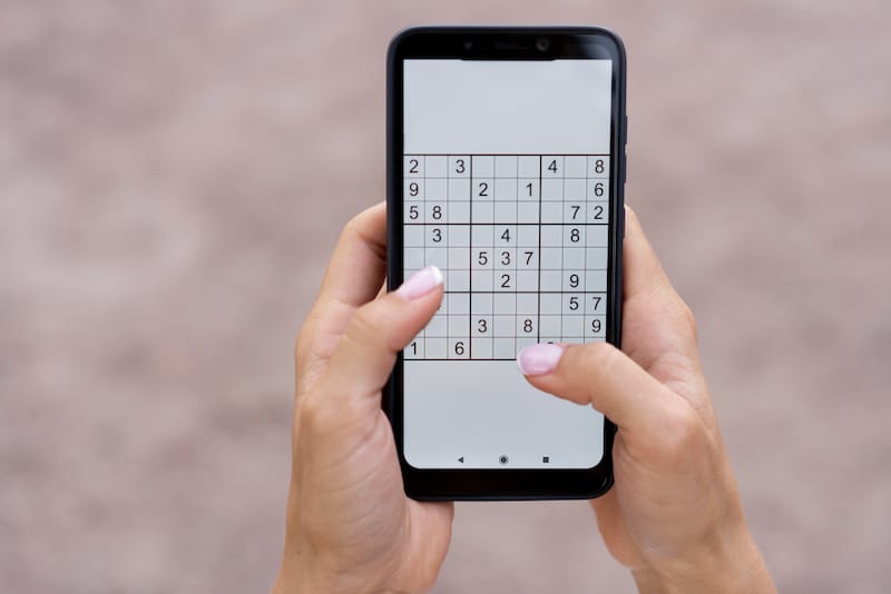 A woman is playing Sudoku on her smartphone