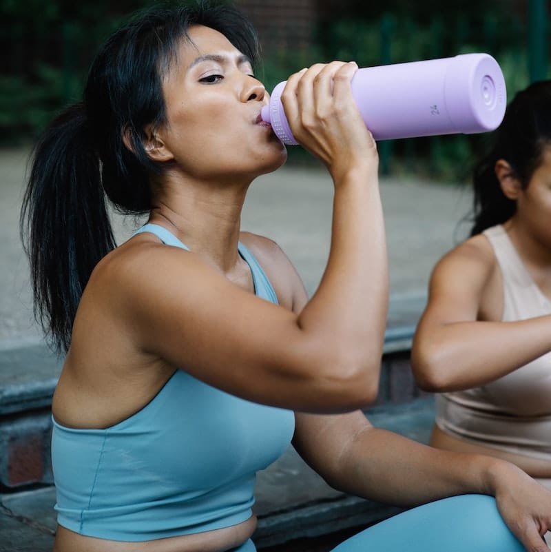 A mom is drinking pre-workout supplement before her workout session