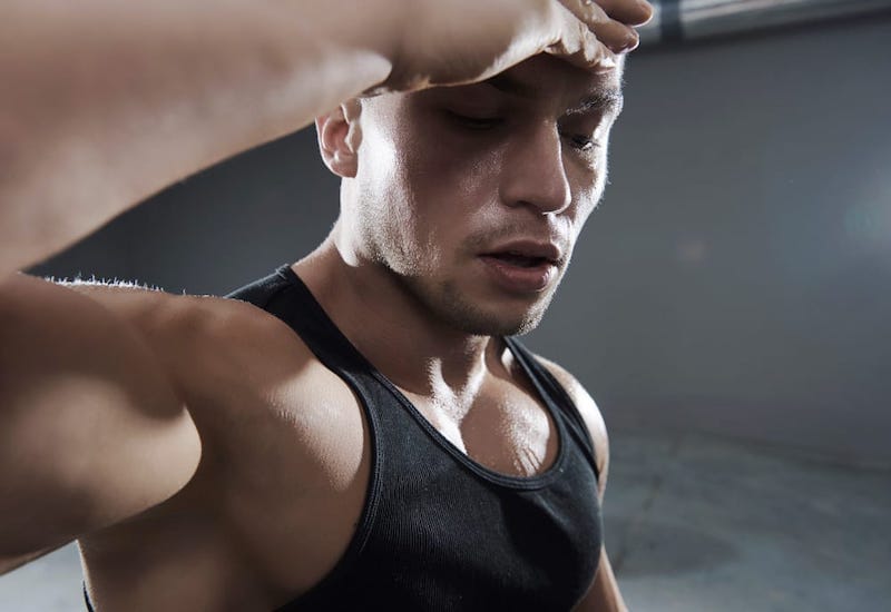 A young man is working out, and as a result, is sweating throughout his body