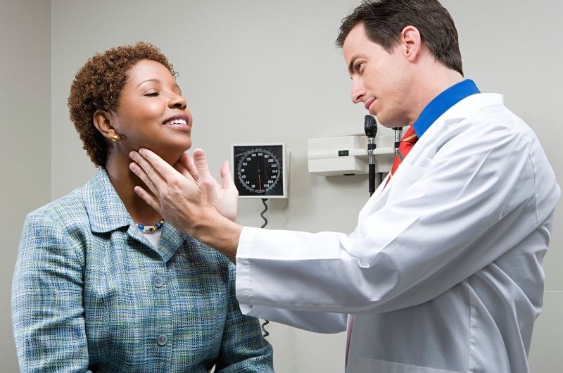 A doctor is checking his patients throat, specifically the hyoid bone