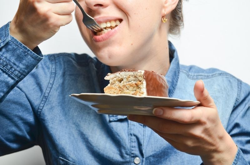 A woman who has the munchies is eating a slice of cake