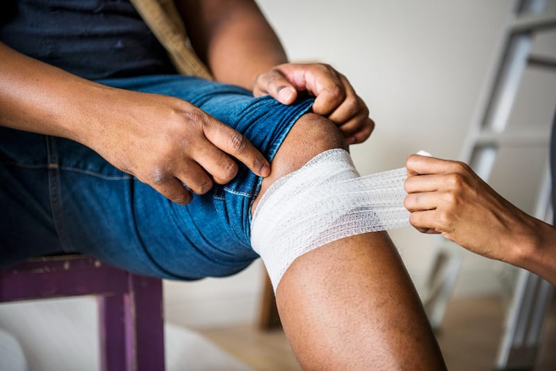 A man is using gauze to tighten an abscess on his leg