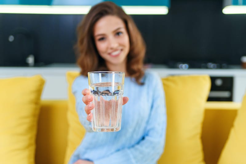 A woman is drinking water to stay hydrated