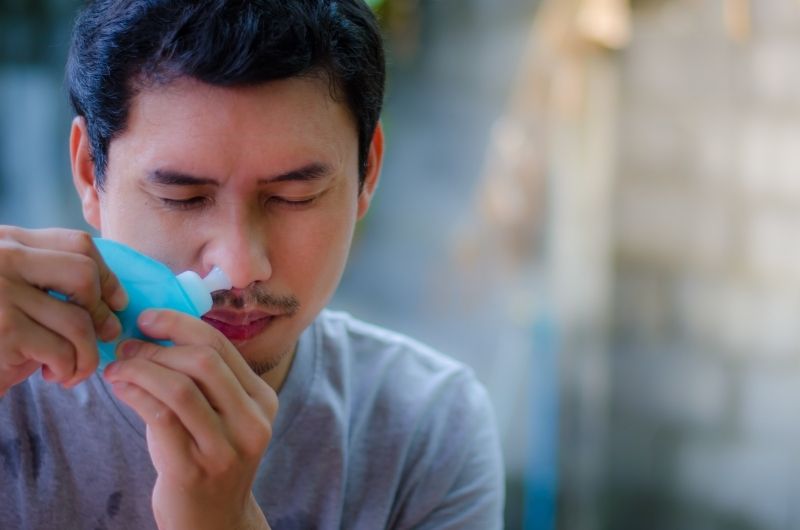 A man is doing a sinus rinse to remove his nasal congestion