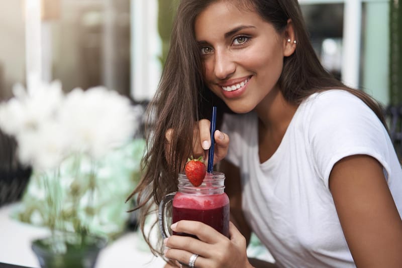 A young woman is drinking a smoothie that's loaded with vitamin B12