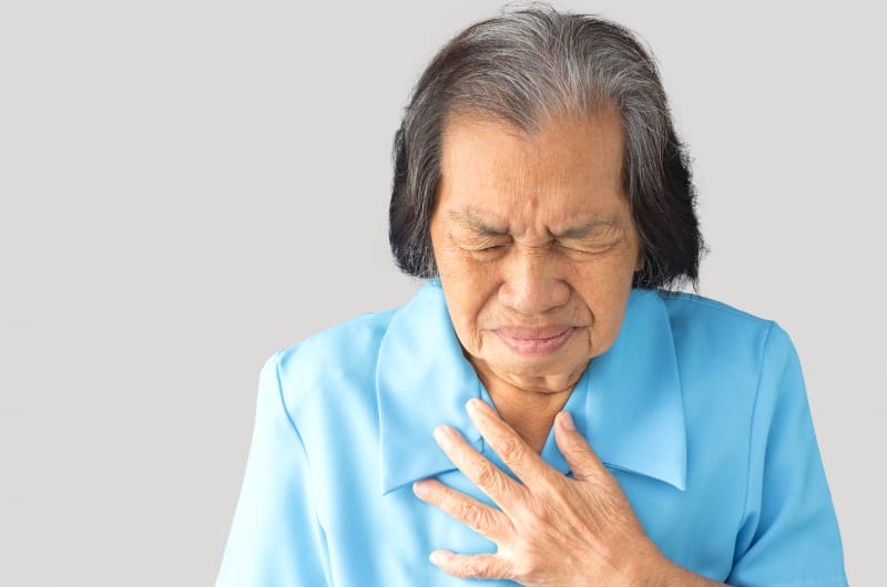 An older woman is experiencing heartburn pain 
