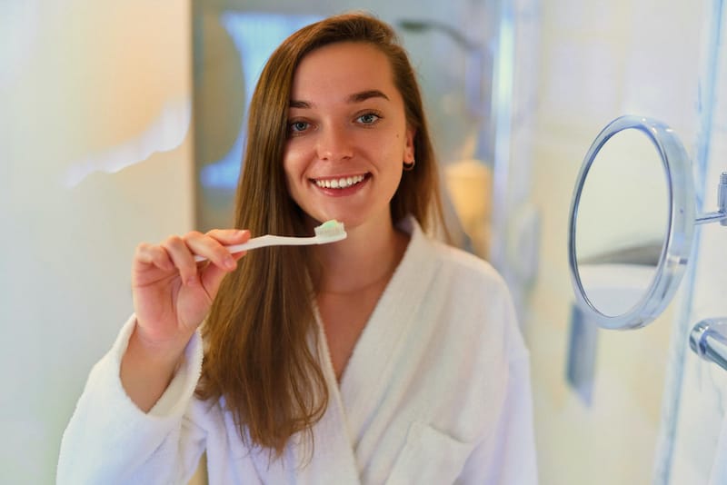 A woman is brushing her teeth after eating dinner
