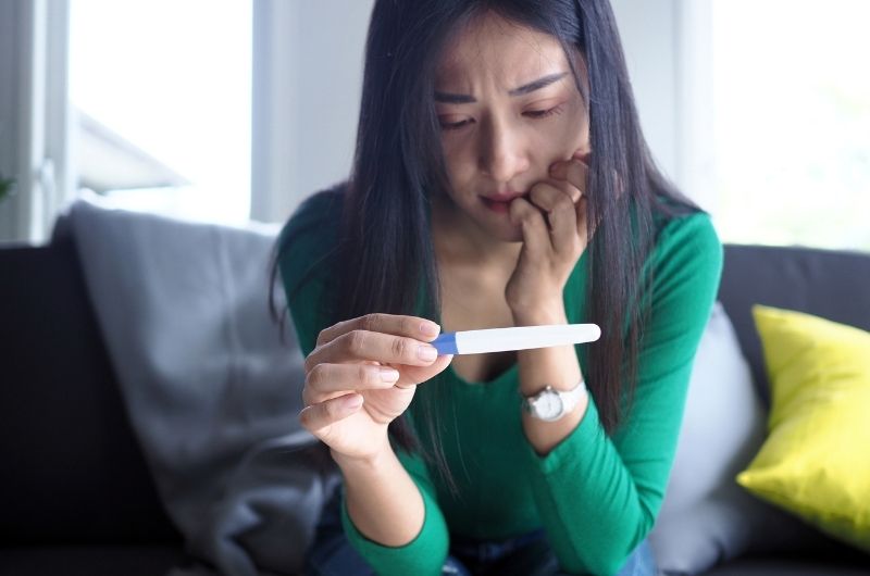 A woman is looking at her pregnancy test that she recently took, to see what the results are.