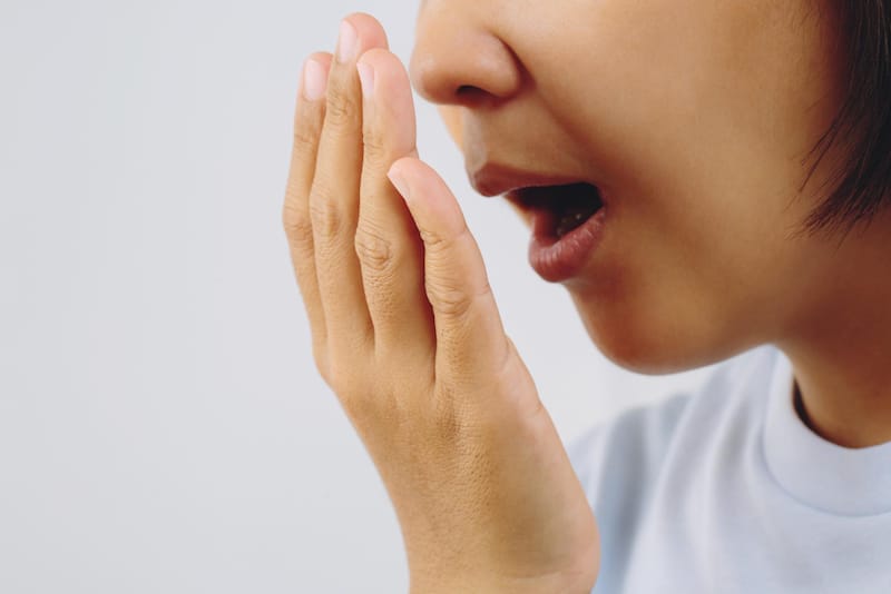 A woman is checking her breath for bad odor