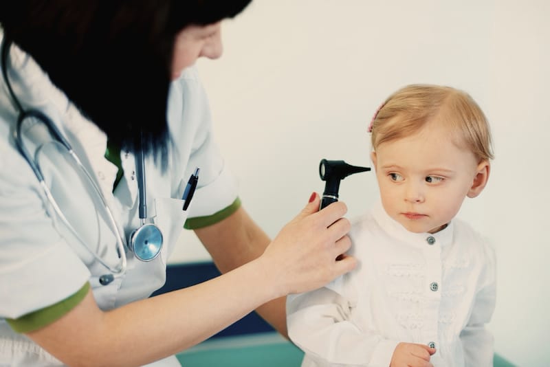 A pediatrician is checking her toddler patients ears during a routine checkup