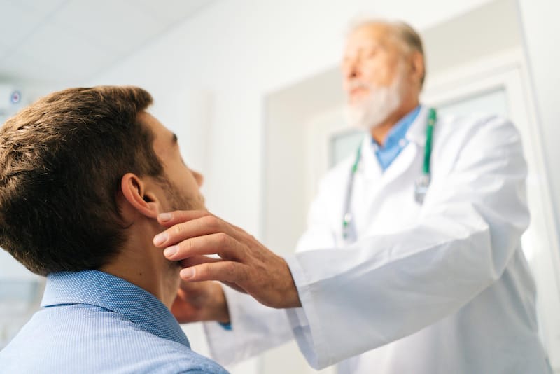 An Otolaryngologist is checking his male patients Adam's apple