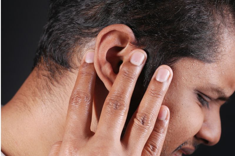 A man is in pain because of a pimple on his ear