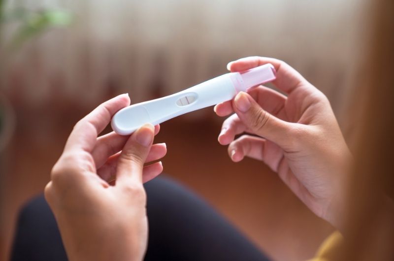 A woman is looking at the pregnancy test that she recently took