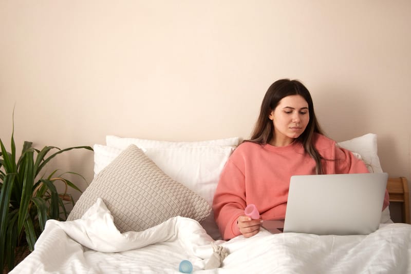 A woman who is ovulating is sitting comfortably in bed researching if using panty liners every day is okay