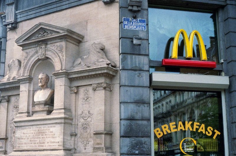 An outside look of a Mcdonald's in Europe that has a breakfast sign
