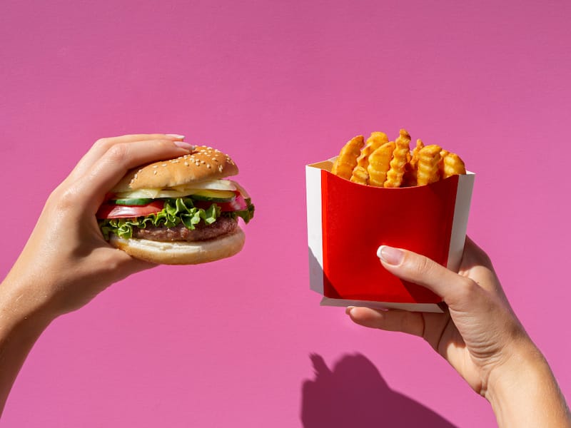 A woman is holding her burger and fries that she got from McDonalds
