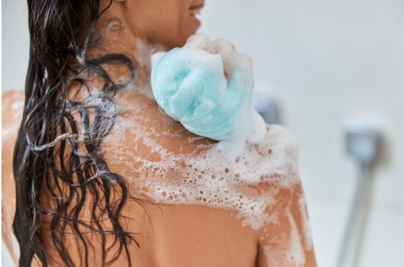 A woman is using a body wash during her shower routine to clean her body