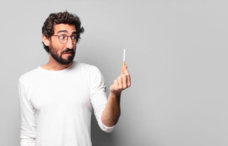 A man is holding a cigarette that he will no longer smoke, as it would affect his penis shrinkage over time.