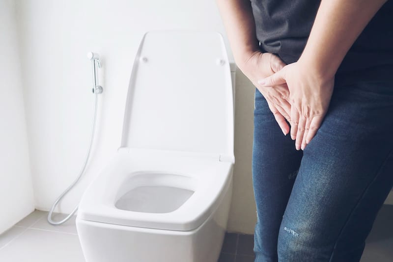 A woman with a bladder infection is holding her bladder area as it's causing her pain and discomfort