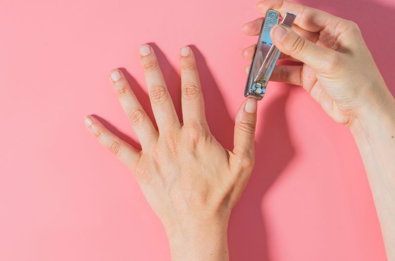 A woman is using a nail cutter to cut her fingernails