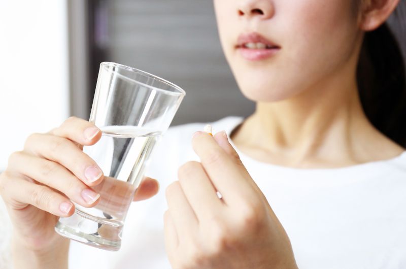 A young woman is about to take her medicine with some water