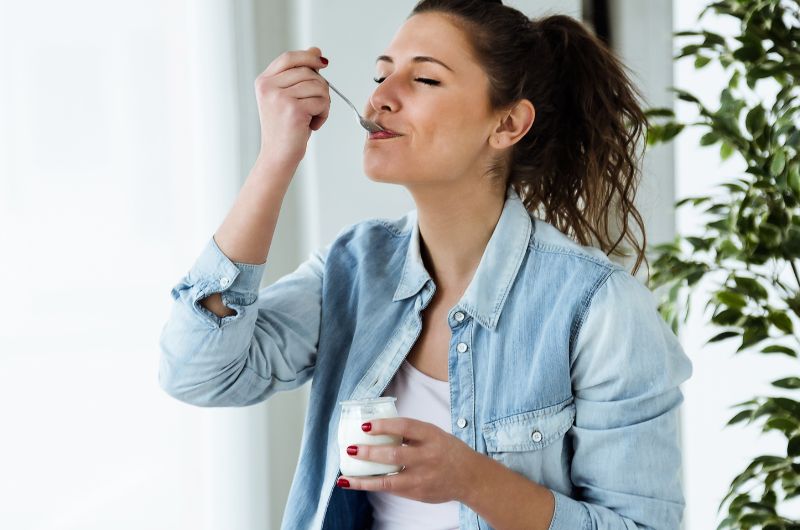 A young woman is having yogurt to increase the probiotics in her diet and help her maintain a healthy vagina.